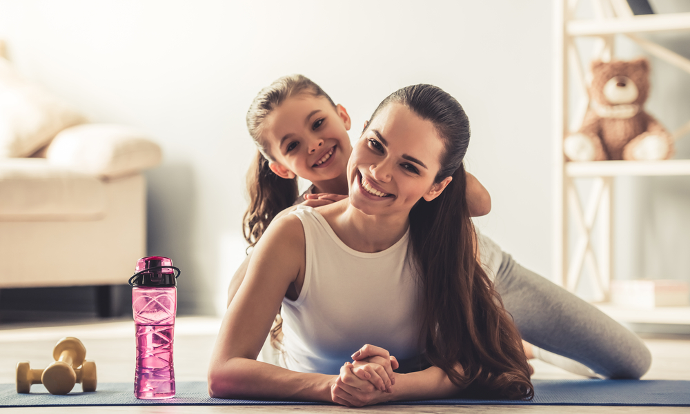 Beautiful woman smiling with a child on the background and bottled water on the side and a depth-of-field on the background